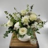 White rose arrangement in a ribbed vase with a small candle beside it
