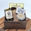 Gift basket with a candle, soap, chocolate, and a tin container in a wooden crate