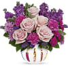 Pink roses and purple flowers arranged in a decorated white vase