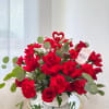 Red roses and carnations in a white woven vase with a heart pick