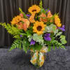 A bright beautiful vase filled with sunflowers, tulips, filler flowers and a