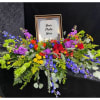 A colorful, commemorative photo spray designed for remembrance or a funeral tribute.