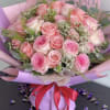 Pink rose bouquet wrapped in lavender paper with a red ribbon