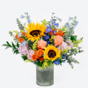 Mixed bouquet with sunflowers, roses, and blue flowers in a metal vase