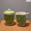 Green polka-dot ceramic mug and matching lidded jar on a table.