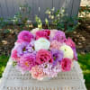 Pink, purple, and white flowers arranged in a low white vase