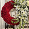 Large crescent floral wreath with red roses and white lilies on easels