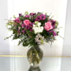 Pink roses and purple daisies in a glass vase