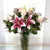 Pink lilies and pale roses in a tall glass vase