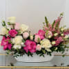 Pink and white roses with pink snapdragons in a white oval vase