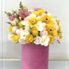Bouquet of yellow and pale pink roses with yellow orchids in a pink box