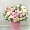 Pink and white roses with ranunculus in a pink hat box