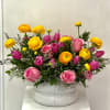 Pink and yellow mixed flower arrangement in a white vase