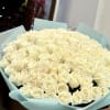 Large bouquet of cream roses wrapped in pale blue paper