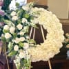 Large floral wreath of white roses and green accents on an easel.