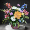 Colorful mixed flower arrangement in a round purple vase