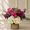 Pink and purple floral arrangement in a gold textured vase