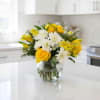 Yellow roses and white daisies in a clear glass vase