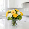 Yellow and white flowers arranged in a clear glass vase