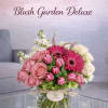A refined, garden-inspired composition featuring blush roses, vivid gerbera daisies, and elegant