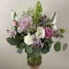 Seasonal light pink, lavender, and white flowers arranged into a vase with