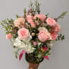 Pink roses and white hydrangeas in a glass vase with a pink ribbon