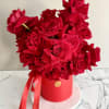Red roses arranged in a round red box with ribbon