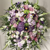 Large standing floral spray with pink and purple flowers on a black easel