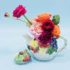 Colorful flowers arranged in a fruit-patterned teapot with a matching lid