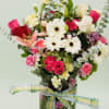 Mixed bouquet of pink and white flowers in a glass vase with a plaid ribbon