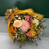 Bouquet of peach and pink flowers wrapped in gold paper