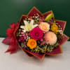 Mixed bouquet with roses, lilies, and a chrysanthemum wrapped in burgundy paper
