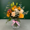 Bouquet of yellow and cream roses with orange flowers in a glass vase