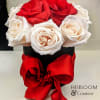 Red and white roses arranged in a black hat box with a red ribbon