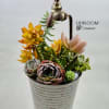 Succulent arrangement in a striped metal pot with a faucet topper