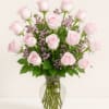 Pink roses and purple filler flowers arranged in a clear glass vase