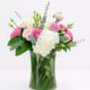 Pink and white flowers arranged in a clear glass vase