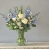 White roses and blue delphinium in a clear glass vase