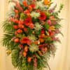 A tall, layered standing spray in warm orange and soft pink-this funeral