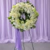 A large circular wreath of white roses, pale daisies, and soft hydrangeas