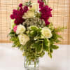 Creamy white roses meet vivid magenta clustered blooms in a clear glass