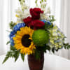A bright sunflower center surrounded by deep red roses and bold blue