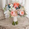 A rounded cluster of peach, blush pink, and white roses creates an