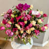 Pink and cream roses with magenta orchids in a vase