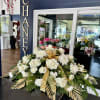 White floral arrangement with roses and chrysanthemums, accented by gold ribbon