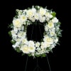White floral wreath on a black easel stand