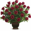 Red roses arranged in a dark pedestal vase