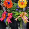 Two novelty flower arrangements with smiling faces in glass vases