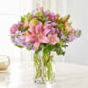 Pink lilies and mixed pastel flowers in a clear glass vase