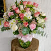 Pink and white rose bouquet in a glass vase with a ribbon